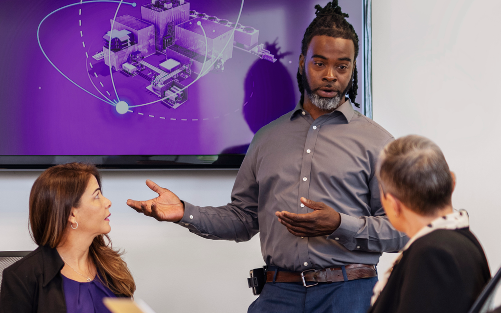 Advisory workshop in front of a grid-visualization screen — energy transformation advisory in practice (Atlas brochure photography)