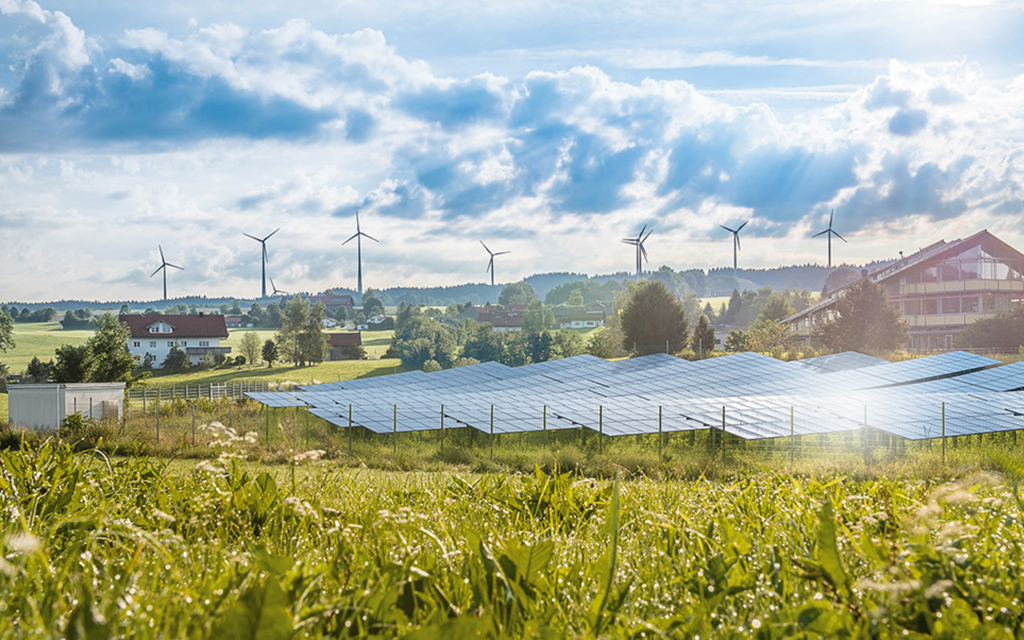 Solar arrays and wind turbines beside a rural community — renewable integration planning and compliance (Atlas brochure photography)