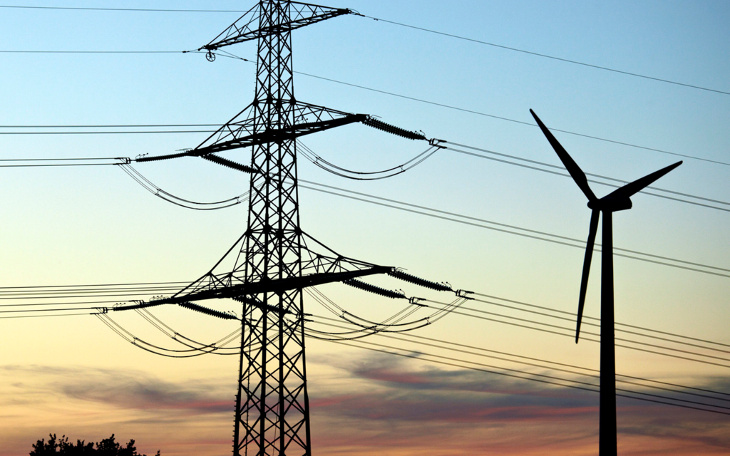 Overhead line and wind turbine at dusk — dynamic line rating unlocks real-time capacity for renewable integration (DLR brochure photography)