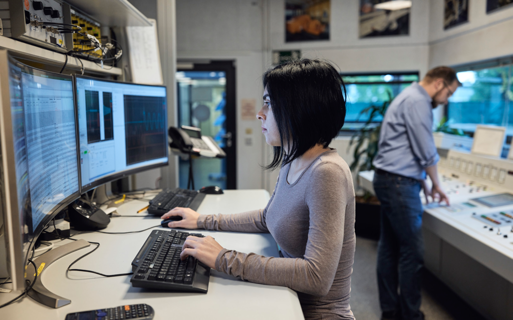 Operators at a control-room workstation — Shield aligns cyber-physical monitoring with real-time grid operations (Shield brochure photography)